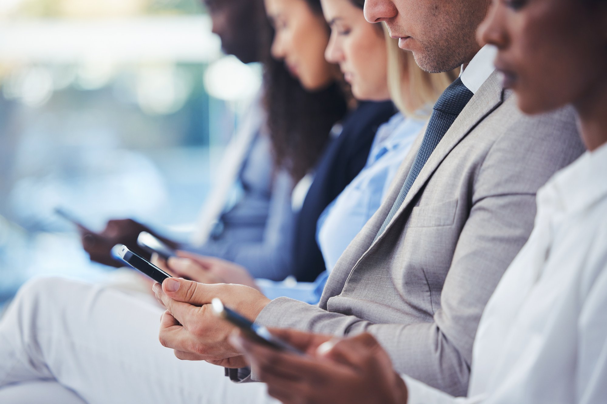 Business professionals on mobile devices, illustrating the need for communication archiving software and secure, compliant messaging.