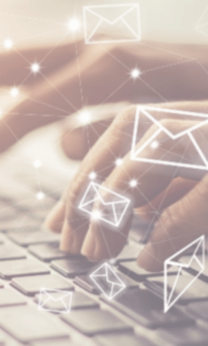 Hands typing on a keyboard with digital email icons floating above, representing the process of migrating PST files to a secure cloud environment.