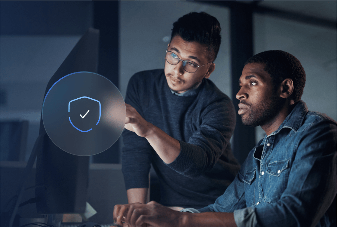 Two male coworkers collaborating on a work project and viewing the monitor with a shield icon representing data security